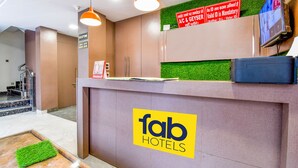 A hotel reception desk with a 'fab hotels' sign, a reception area, and a television screen. - Fabexpress Ganges Pride (Haridwar)