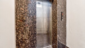 An elevator with a sign indicating it is a fire escape. - Fabexpress Ganges Pride (Haridwar)