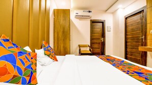 A hotel room with a bed, a chair, and a wardrobe. - Fabexpress Ganges Pride (Haridwar)