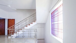 A staircase with metal railings, a wooden door, and a window with red bars. - Fabexpress Kovalam Residency (Tirupporur)