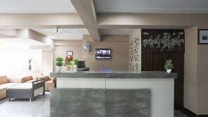 Et moderne receptionsområde med en marmor disk, et tv ophængt på væggen og en dekorativ vægpanel.