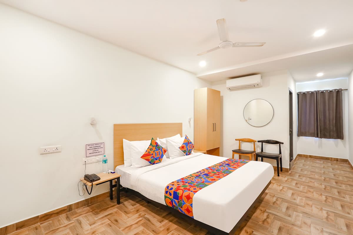 Habitación de hotel con una cama grande, un escritorio con teléfono, una silla y un espejo en la pared.
