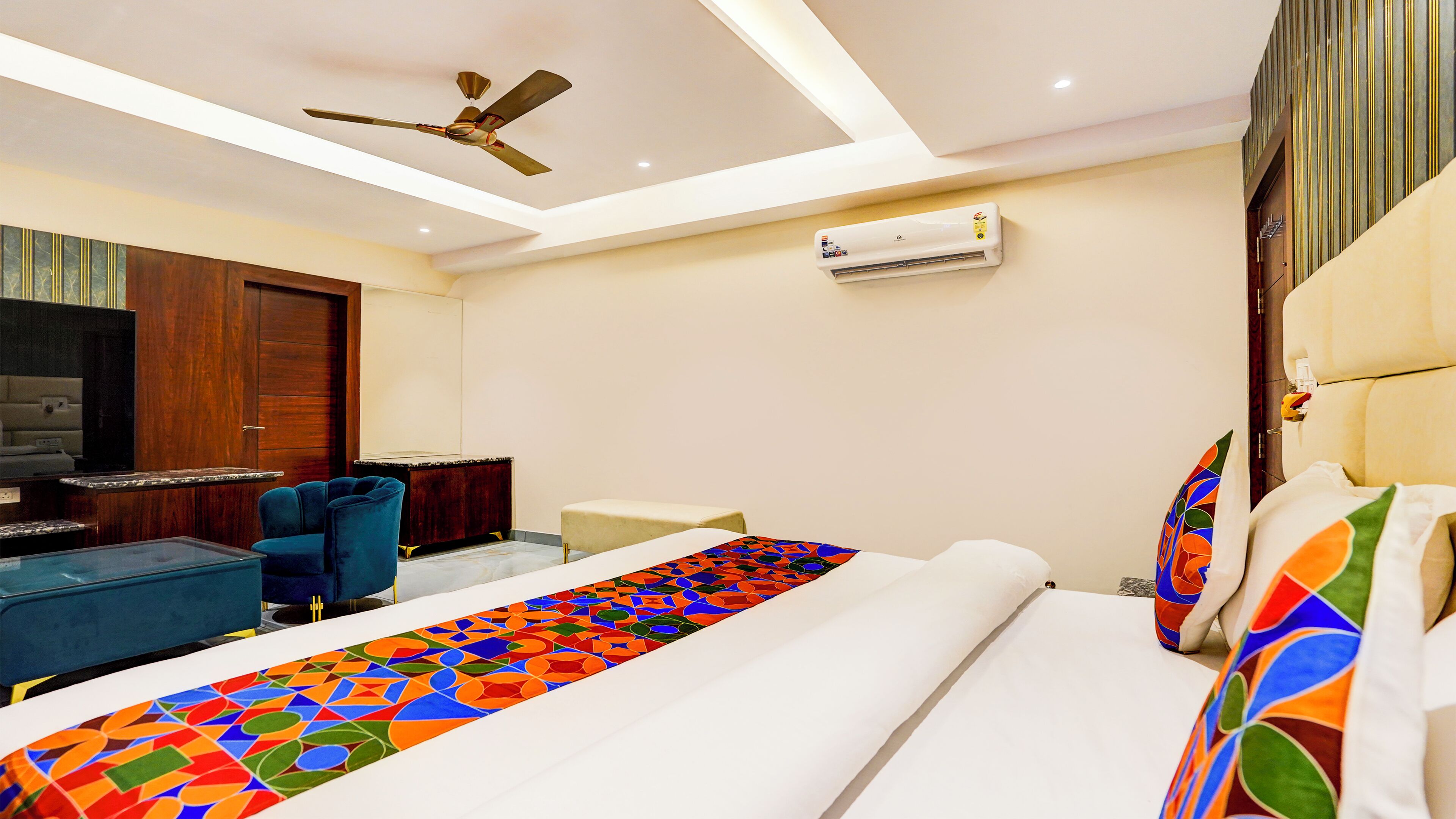 A hotel room with a bed, a desk, a chair, a ceiling fan, and an air conditioning unit.