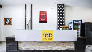 A reception desk with a 'fab hotels' sign, a 'kinley' vending machine, and a 'check in time: 12 PM' disclaimer on the wall. - Fabexpress Raj Tourist (Nashik)