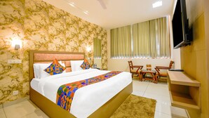A hotel room with a large bed, a desk, a chair, a television, and a ceiling fan. - Fabhotel Prime Victoria Regency (Mohali)