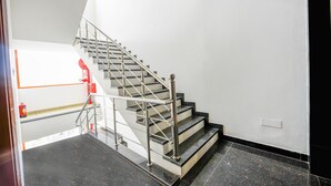 A staircase with metal railings and a fire extinguisher on the landing. - Fabhotel Prime Victoria Regency (Mohali)