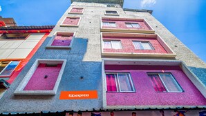 Un edificio de varios pisos con una fachada singular que presenta colores vibrantes y numerosas ventanas.