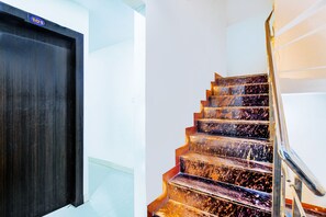 A staircase with a dark wooden door and a handrail. - Fabhotel Mantra Residency (Ujjain)
