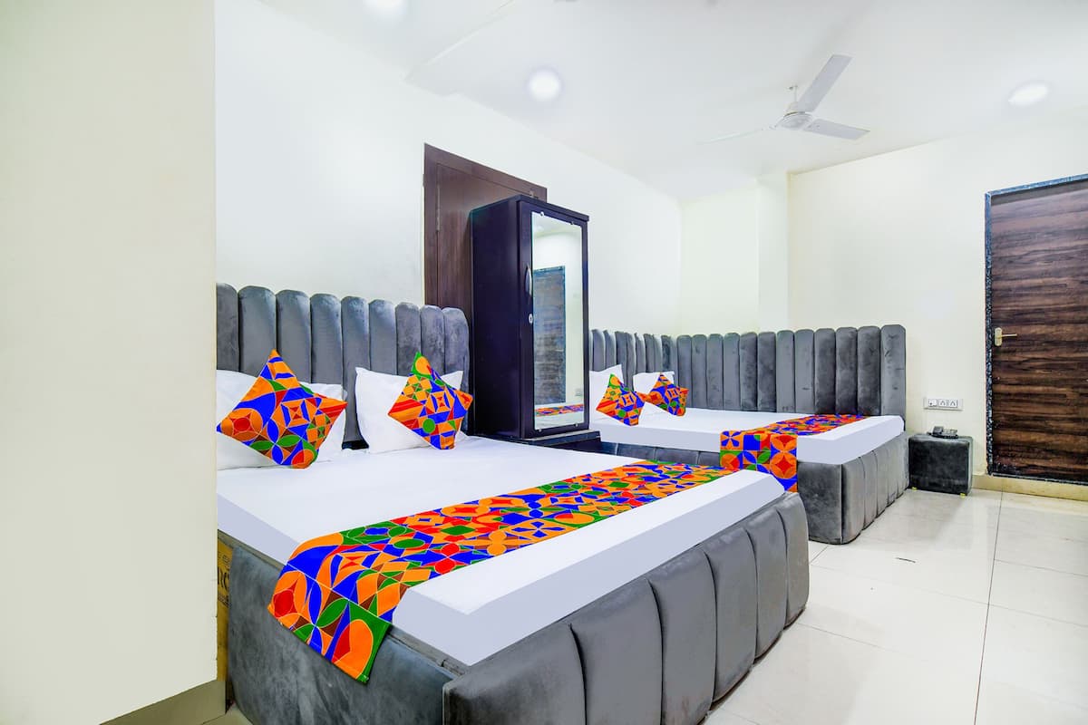 Un dormitorio moderno con dos camas, un espejo grande y un ventilador de techo.