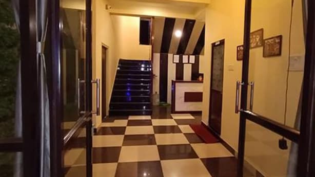 A hotel hallway with a checkered floor, a staircase, and a reception area. - Fabhotel Ocean Bird (Diamond Harbour)