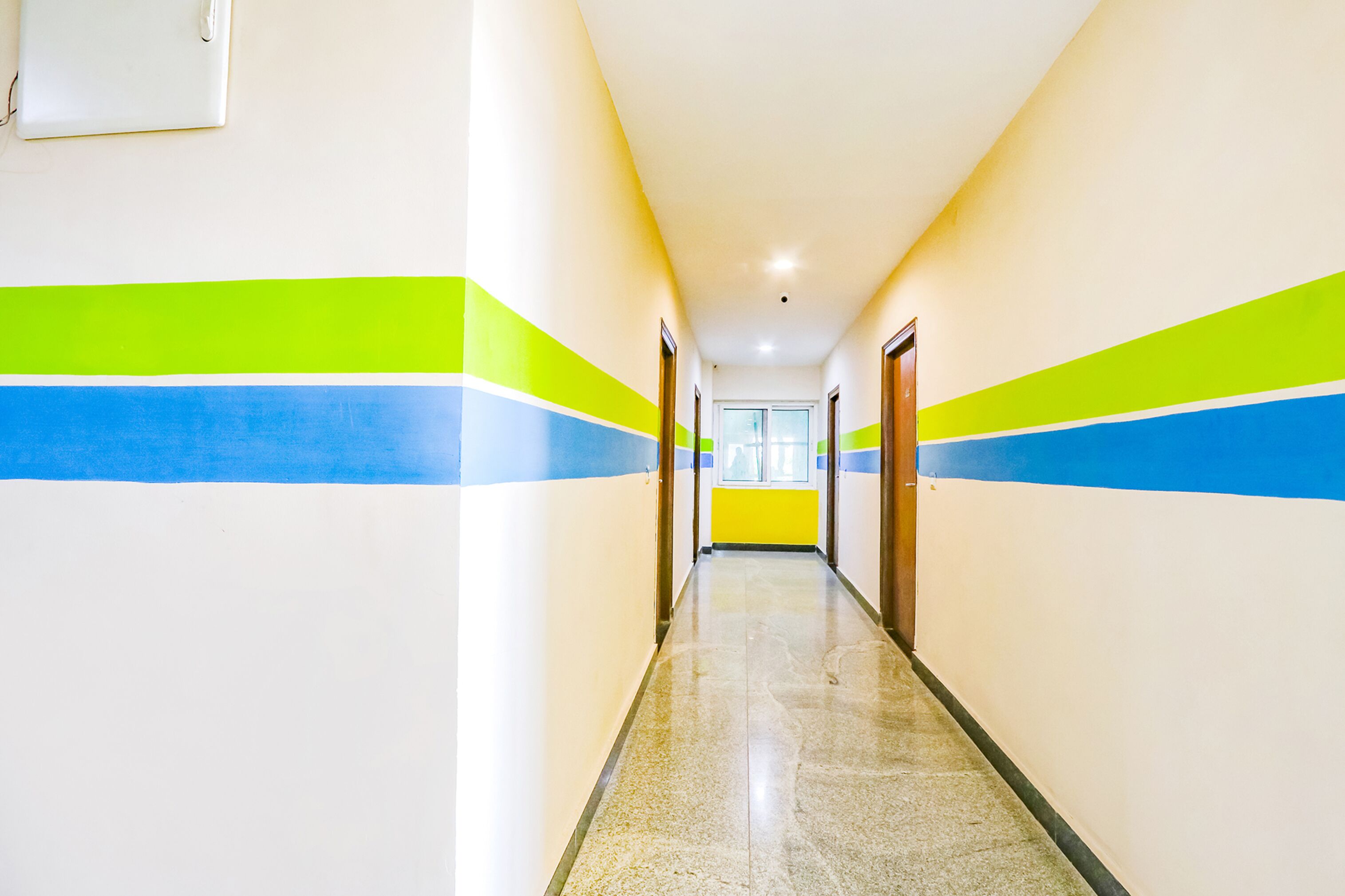 A long, narrow hallway with white walls and green and blue stripes.
