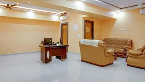 Una habitación amplia con un escritorio de madera, dos sofás de cuero y un sillón grande de cuero.
