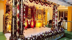 Un escenario decorado con estructuras doradas ornamentales, arreglos florales y una estructura central que recuerda a un altar.