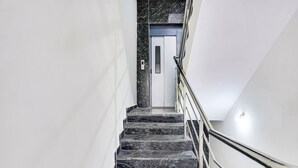 A staircase with marble steps and metal railings leading to a door. - FabHotel Grand Aarvi Prime - Nr. Hafeezpet, Madeenaguda (Hyderabad)