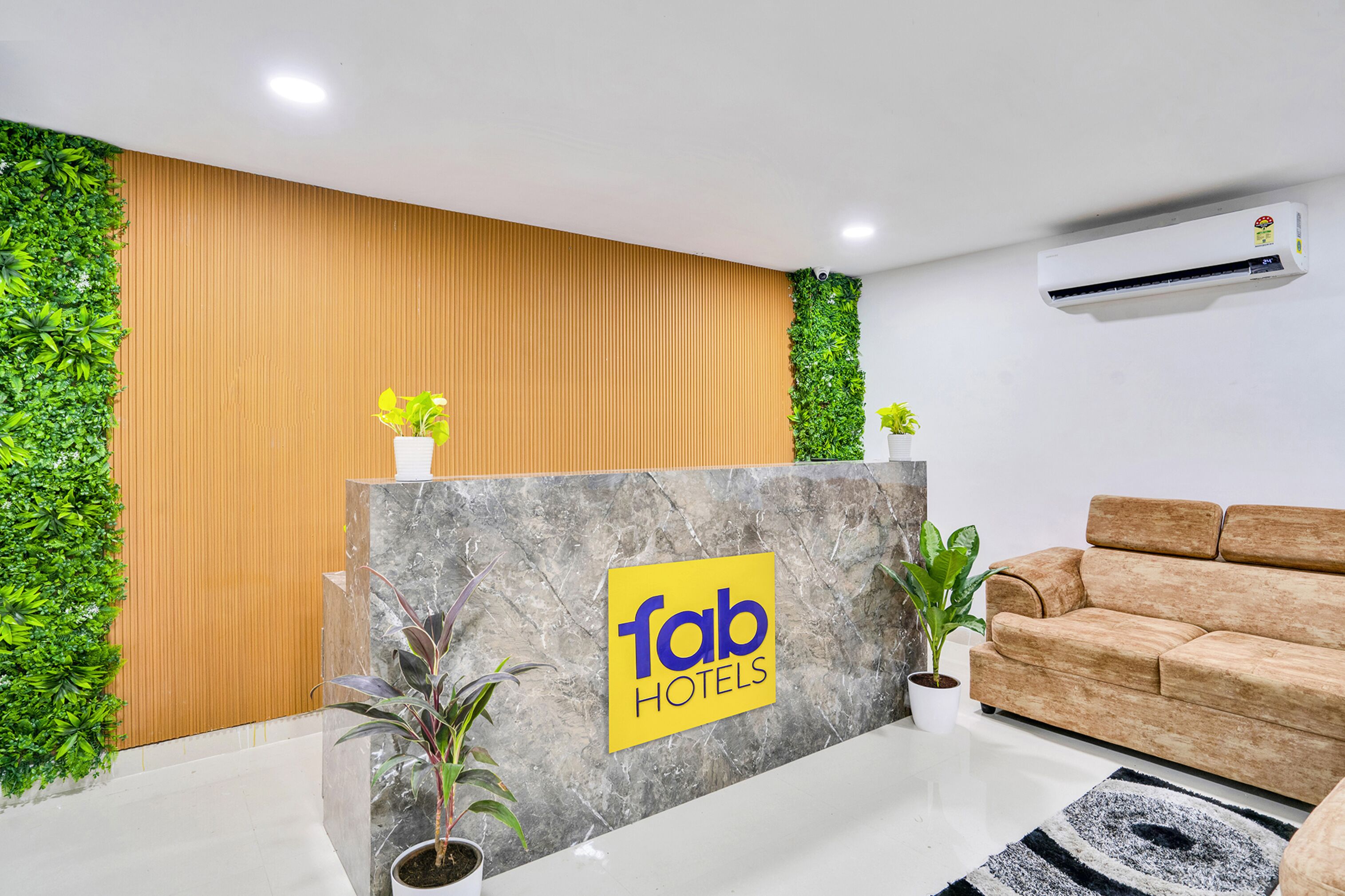 Un área de recepción con un panel de madera en la pared, un mostrador de mármol y un sofá.