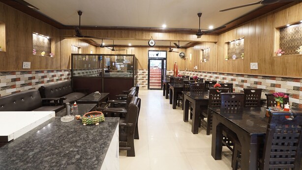 Un restaurant aux murs en bois, doté de ventilateurs de plafond et d’un espace central aménagé avec des tables et des chaises.