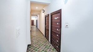 Un couloir doté d’un sol carrelé, de murs blancs et de portes en bois portant des étiquettes.