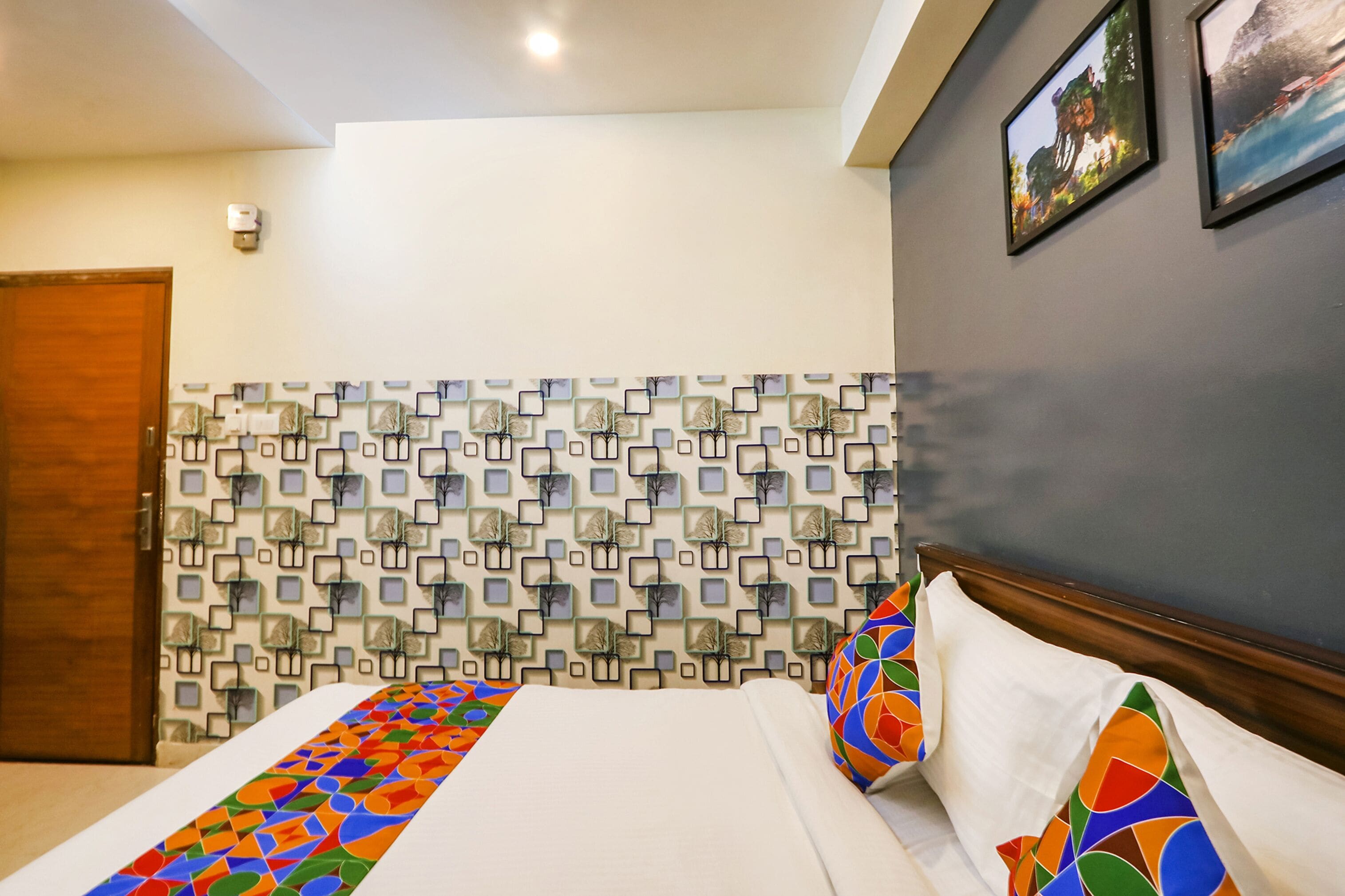 Ein Hotelzimmer mit Wandverkleidung mit Muster, einem Bett mit bunter Bettwäsche und einer Holztür.
