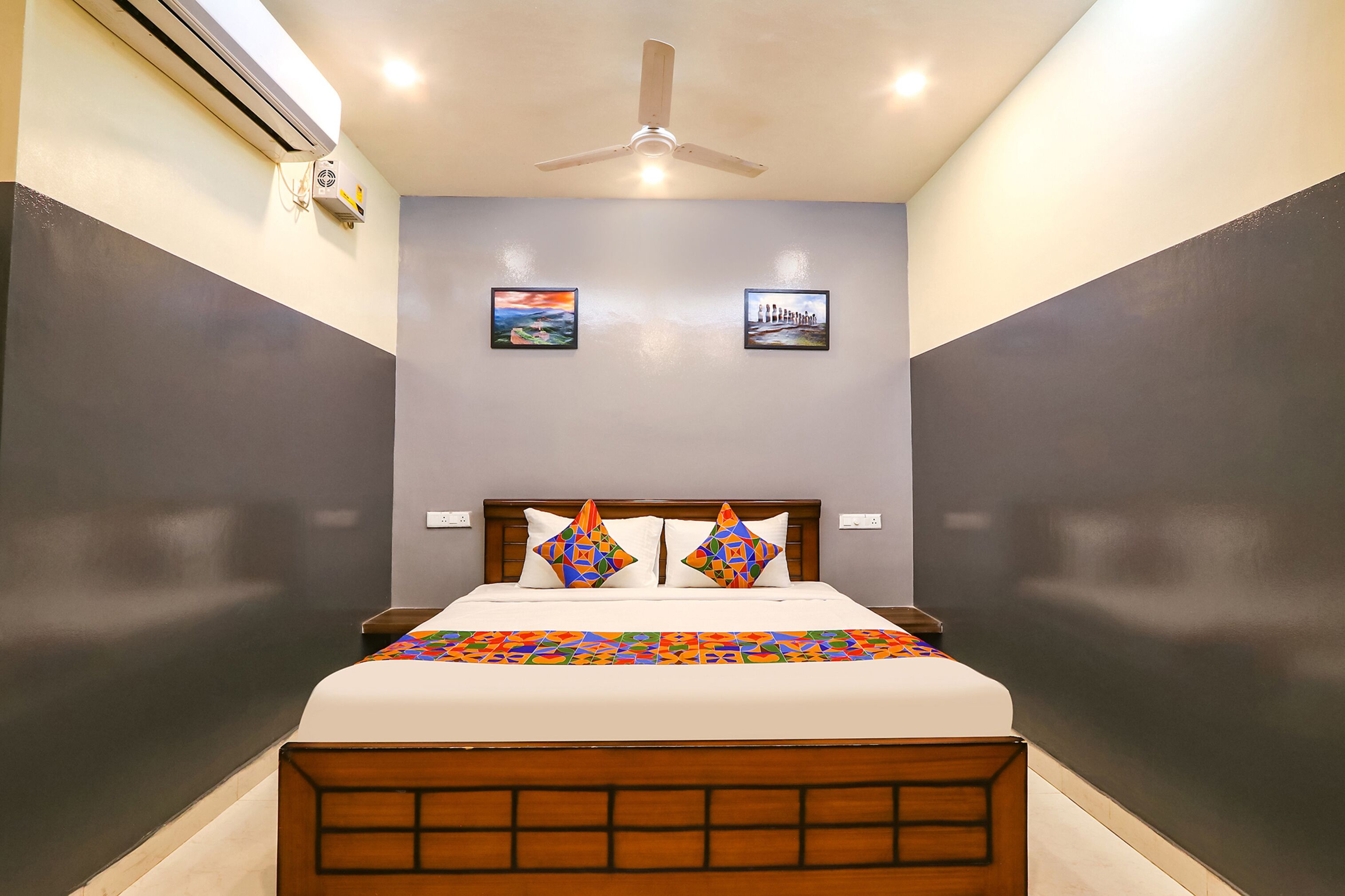 A bedroom with a bed, a ceiling fan, and two wall-mounted air conditioning units.