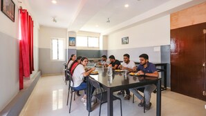 A dining area with a long table, chairs, and a ceiling fan. - FabHotel Starhood - Manikonda (Hyderabad)