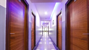 A long, narrow hallway with wooden doors on both sides and a polished floor. - FabHotel Starhood - Manikonda (Hyderabad)
