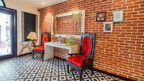 Una habitación con pared de ladrillo, suelo estampado, un escritorio con silla y una ventana con vistas.