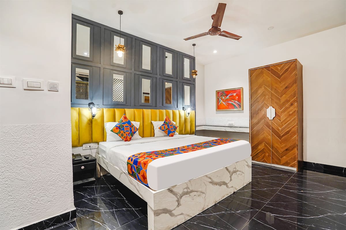 A modern hotel room with a large bed, a ceiling fan, and a wooden door.