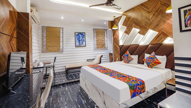 Una habitación de hotel moderna con cama, escritorio, silla, ventilador de techo y vistas a la ciudad.