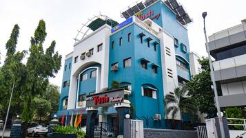A hotel with a blue and white facade, a sign reading "Yash Regency," and a gated entrance.