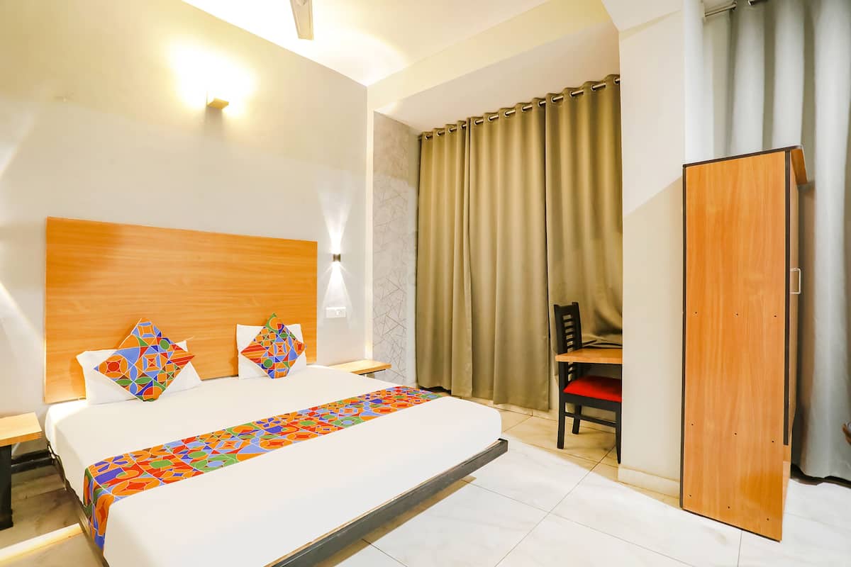 Ein Hotelzimmer mit einem großen Bett, einem Holzkopfende, einem Nachttisch, einem Sessel und einem Kleiderschrank.