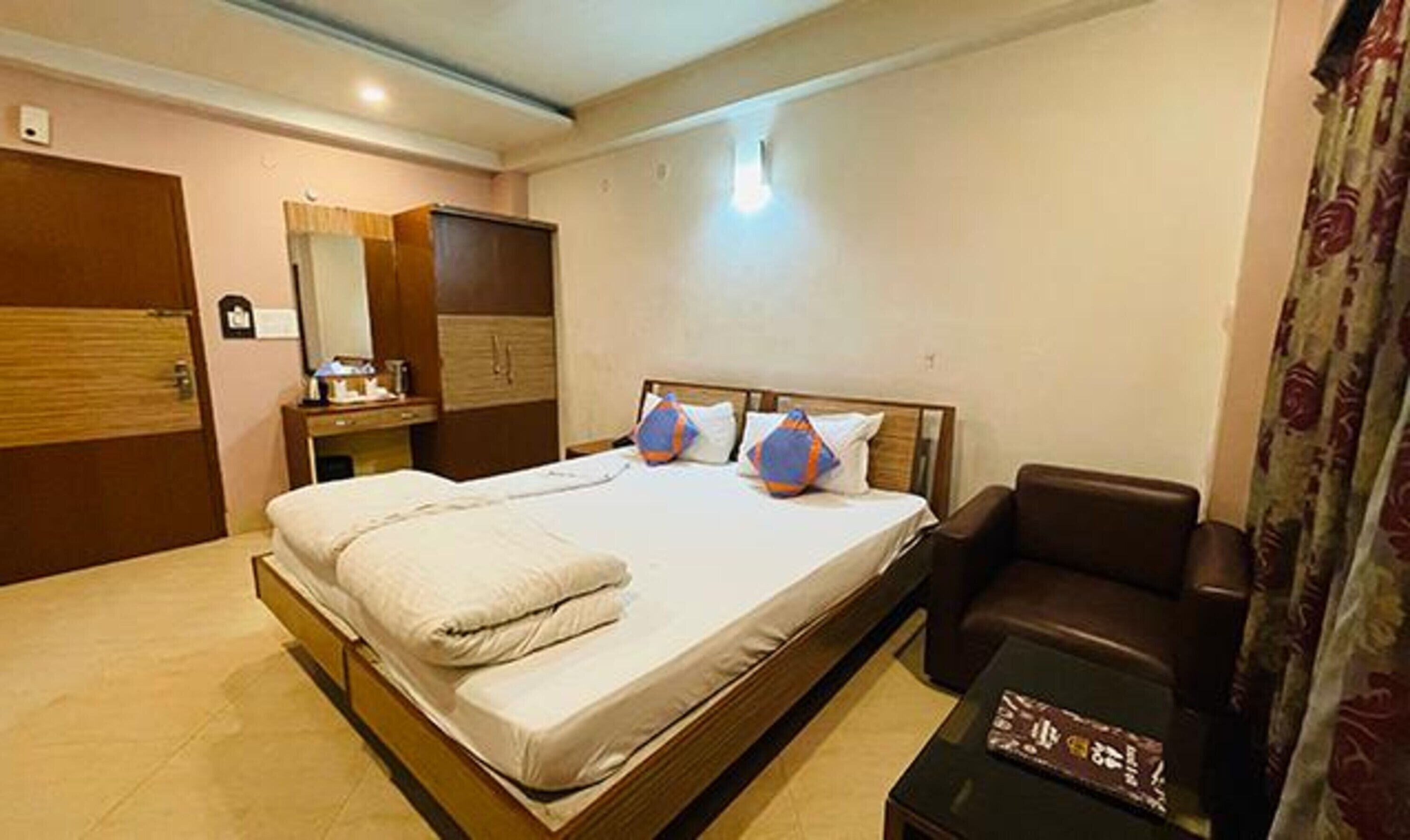 Quarto de hotel com cama, escrivaninha, cadeira e guarda-roupa.
