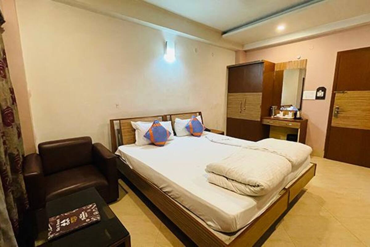 Ein Hotelzimmer mit einem großen Bett, einem Nachttisch, einem Sessel, einem Kleiderschrank und einem Spiegel.