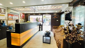 A hotel lobby with a reception desk, a sofa, and a decorative plant. - Fabhotel Prime Gananayak (Jalpaiguri)