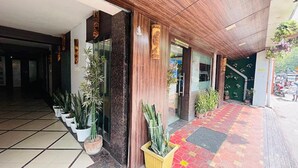 A hotel entrance with a tiled floor, potted plants, and a wooden facade. - Fabhotel Prime Gananayak (Jalpaiguri)