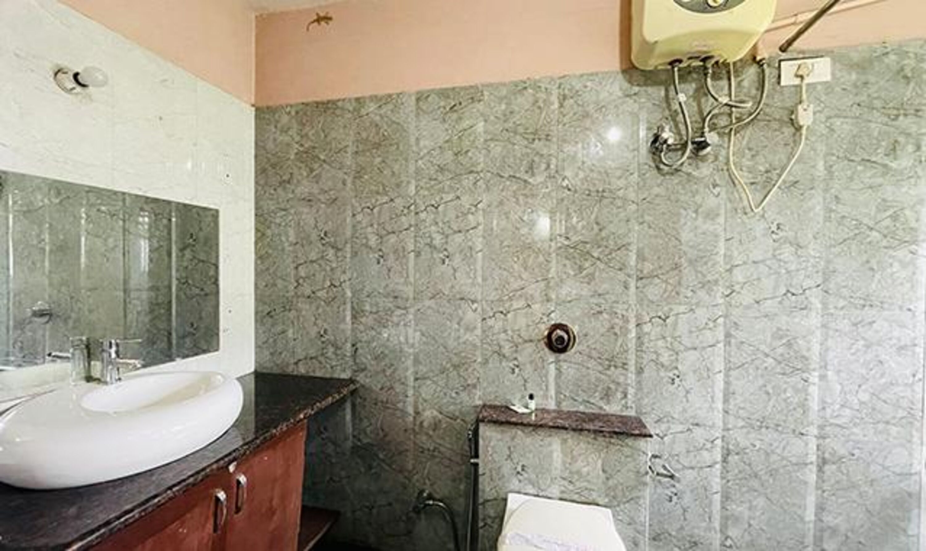 A bathroom with a marble wall, a sink, and a mirror.
