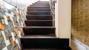 A staircase with a patterned wall on one side and a textured wall on the other. - FabExpress Sagar Plaza (Dehradun)