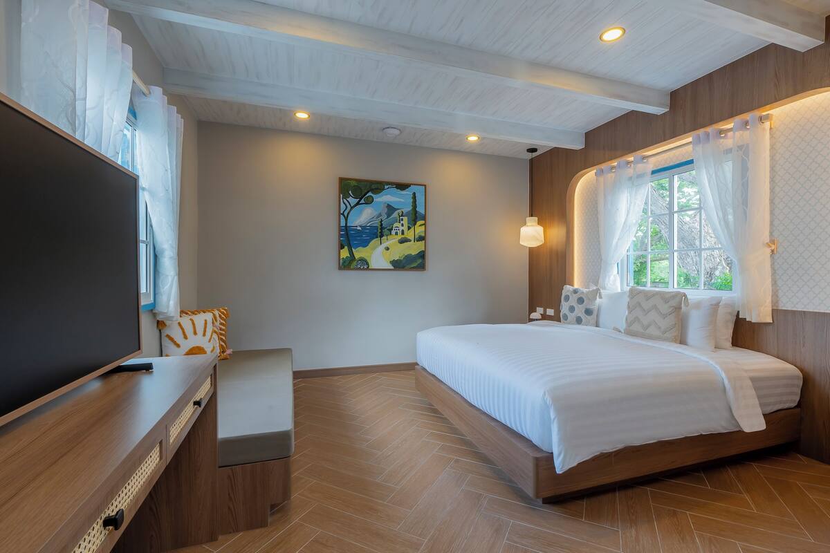 Een slaapkamer met een groot bed, een televisie en een schilderij aan de muur.