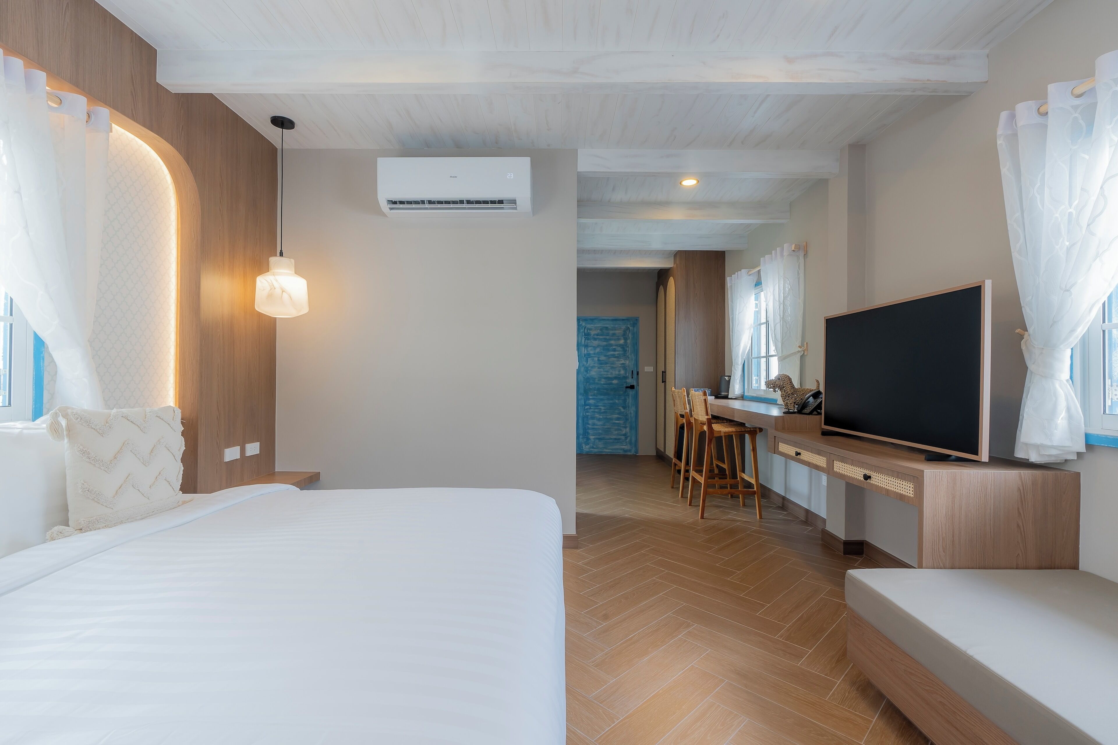 A modern hotel room with a large bed, a TV, and a dining area.