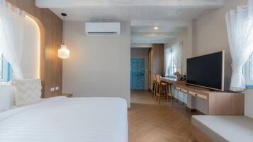 A modern hotel room with a large bed, a TV, and a dining area.