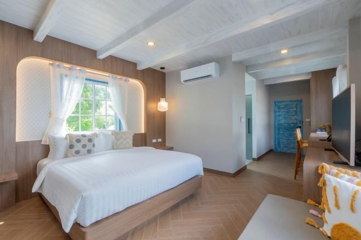 A modern bedroom with a large bed, built-in bedside tables, a TV, and a view of the outdoors.