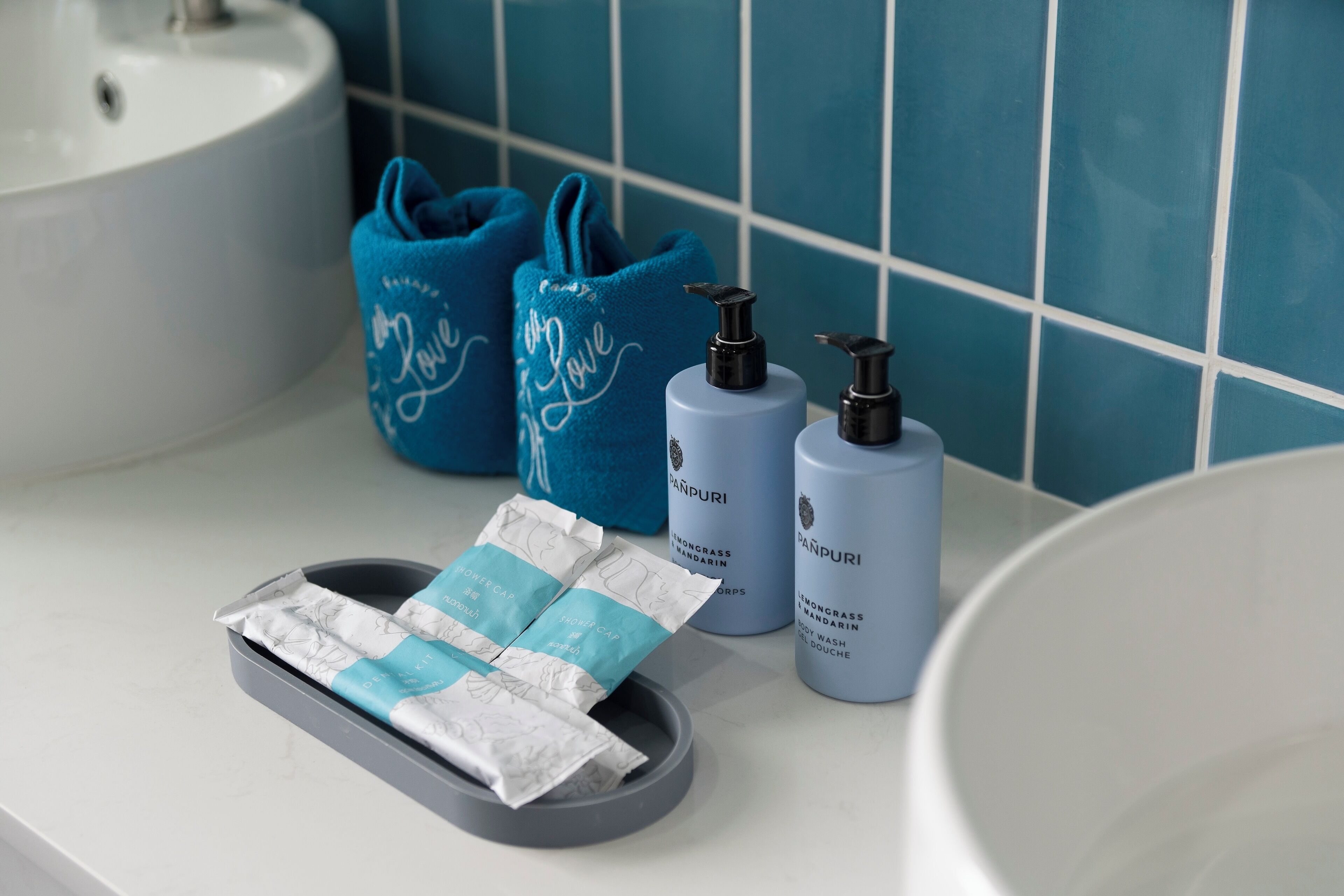 Un baño con un lavabo, dos toallas azules y dos botellas de jabón para manos.