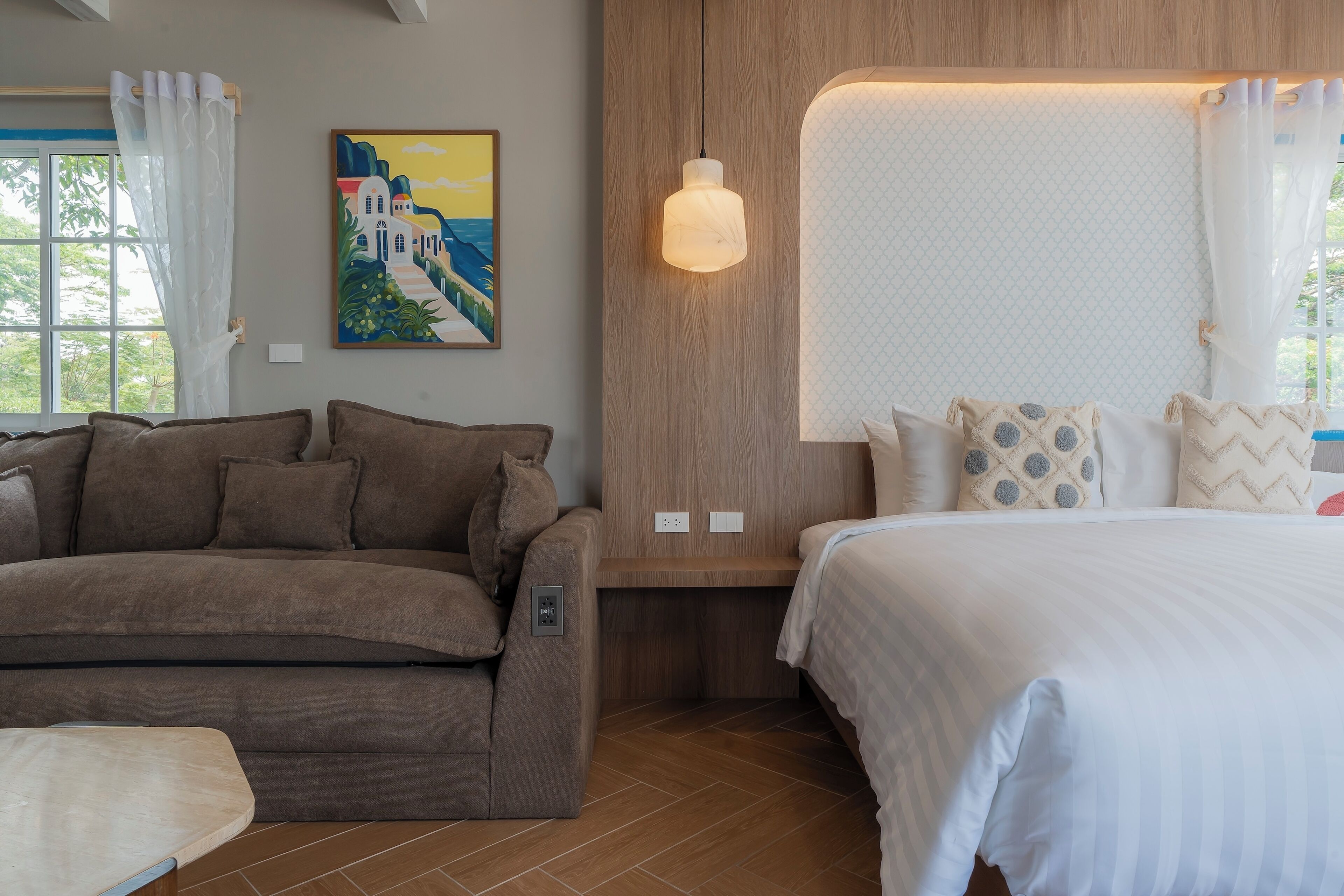 A modern room with a sofa, a bed, a wall-mounted light, and a painting.