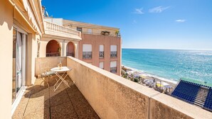 Un balcón con mesa y sillas, con vista a la playa y al mar.