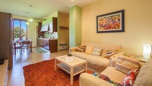 A living room with a sofa, a coffee table, and a dining area with a table and chairs.