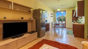A modern kitchen with a large refrigerator, microwave, and a flat-screen TV on a wooden cabinet.