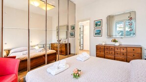 Ein Schlafzimmer mit einem großen Spiegel, einer Holzkommode, einem Bett mit Handtüchern und einem roten Sessel.