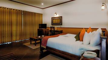 A hotel room with a large bed, a television, a desk, and a chair.