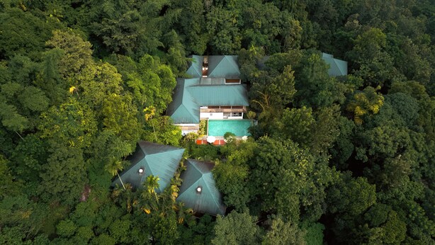 An aerial view of a resort with multiple buildings surrounded by dense forest. - The Hive Wayanad By Kondody Hotels (Vythiri)