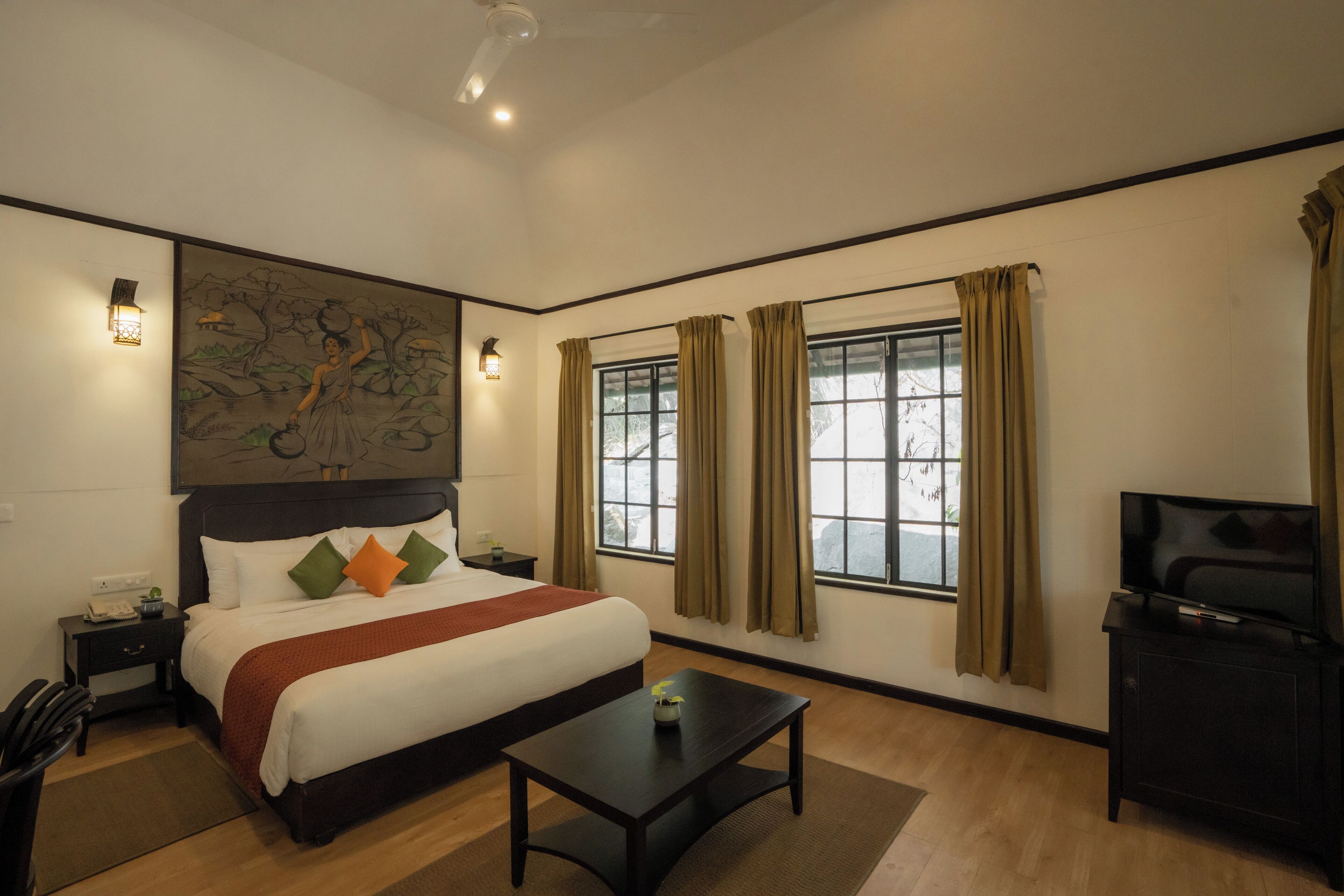 A hotel room with a bed, a desk, a TV, and a window with curtains.