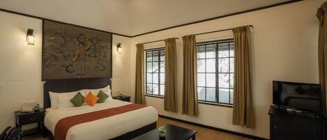 A hotel room with a bed, a desk, a TV, and a window with curtains.